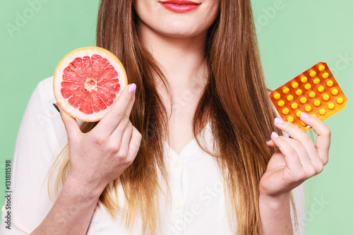 Woman holds grapefruit and pills blister pack vitamin c photo