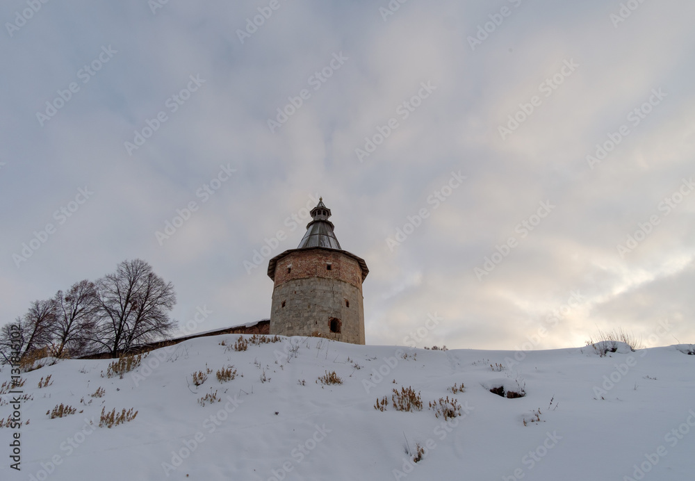 Зимний пейзаж в видом башни старинного кремля на фоне закатного неба 