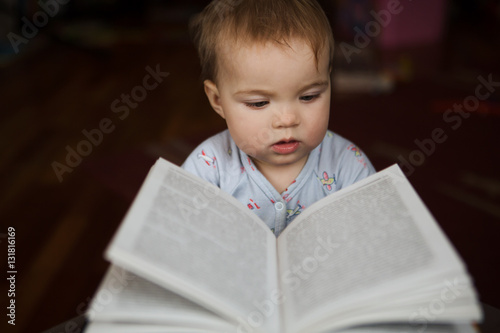 Portrait of an adorable baby reading a book at home    