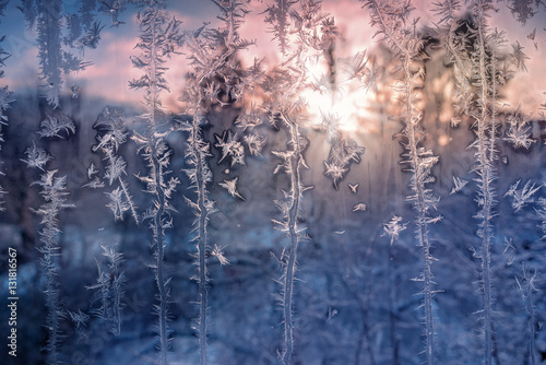 Frost patterns on the window glass in the rays of the setting sun © fotiy