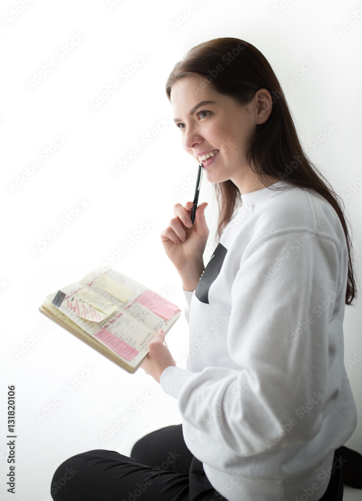 Beautiful young woman sitting with notebook on windowsill Beautiful young woman sitting with notebook on windowsill