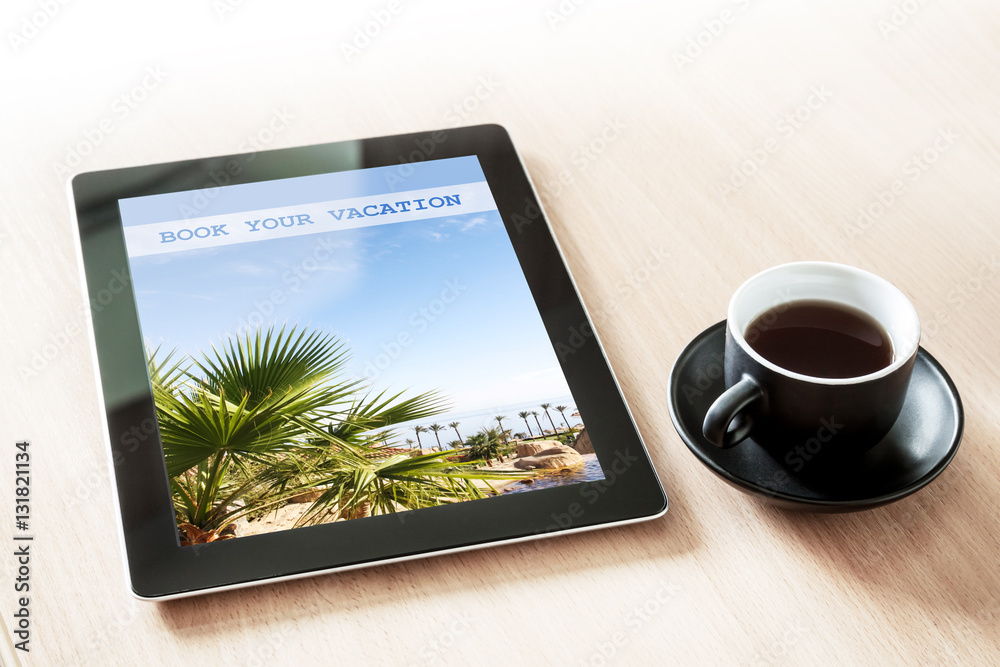 Tablet computer with sea view wallpaper, on the desk with a cup of coffee, booking vacation idea Tablet computer with sea view wallpaper, on the desk with a cup of coffee, booking vacation idea