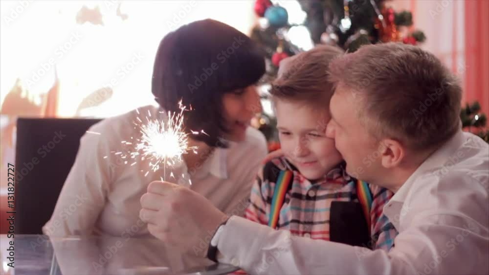 Happy family and Bengal fire. Mother holding sparkler, then she and father kissing child while he looking at light. Slow motion