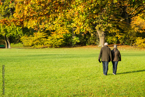 Coppia di anziani a passeggio in autunno all'Englischer Garten di Monaco di Baviera, Germania photo