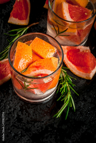 Refreshing summer detox cocktail of grapefruit and rosemary, on black table, copy space 