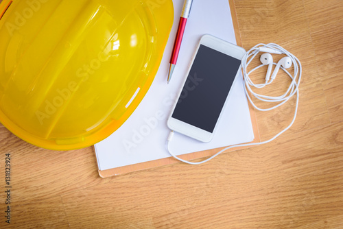 safety helmet, clipboard, notebook, pen on wooden table