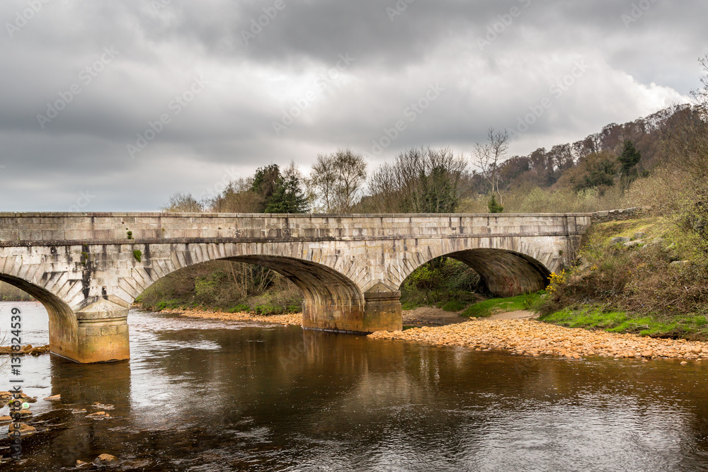Old ancient stone bridge over calm river, beautiful Irish landscape. Scenic view.