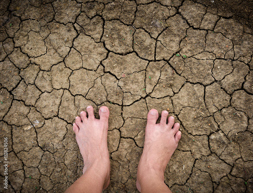 Barefoot standing on dry and cracked ground