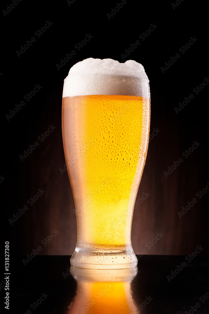 light beer in frosty glass over dark wooden background