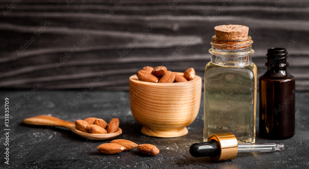 cosmetic almond oil in glass bottle on dark wooden background Stock