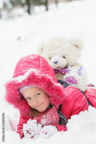 Girl with teddy bear in the winter forest.