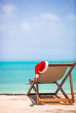 Christmas on the beach - chair with Santa hats at sea. Christmas vacation concept