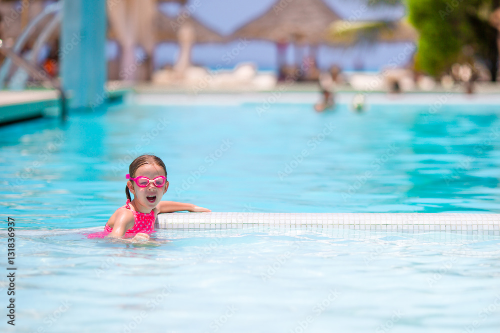 Little happy adorable girl swimming in outdoor pool