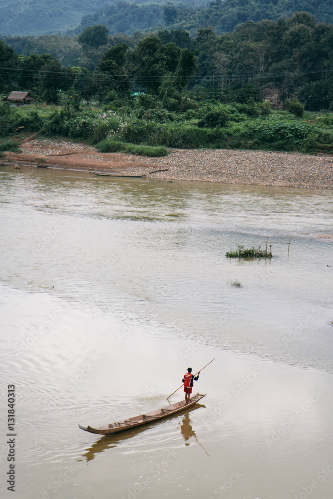 A man crossing the Mekong River on his wooden boat A man crossing the Mekong River on his wooden boat