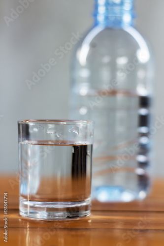 Drinking water in the glass and in the bottle on a wooden table.