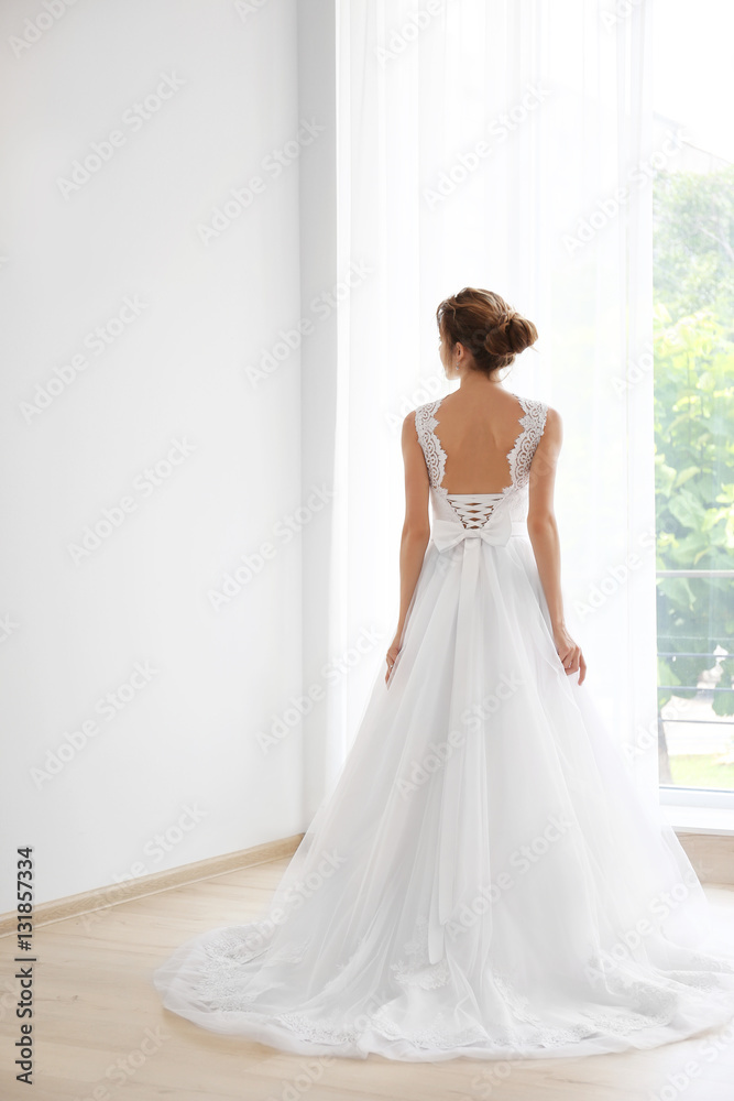 Bride in a beautiful wedding dress standing near window Bride in a beautiful wedding dress standing near window
