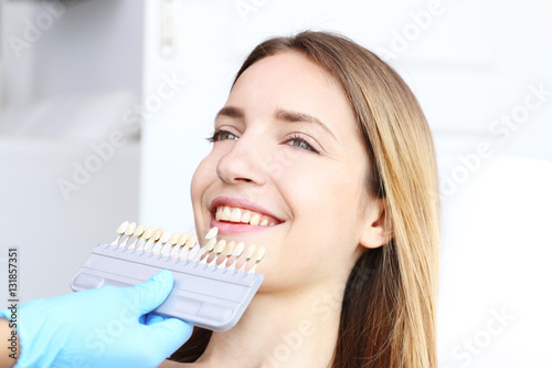 Young woman at dentist office checking and selecting colour of the teeth