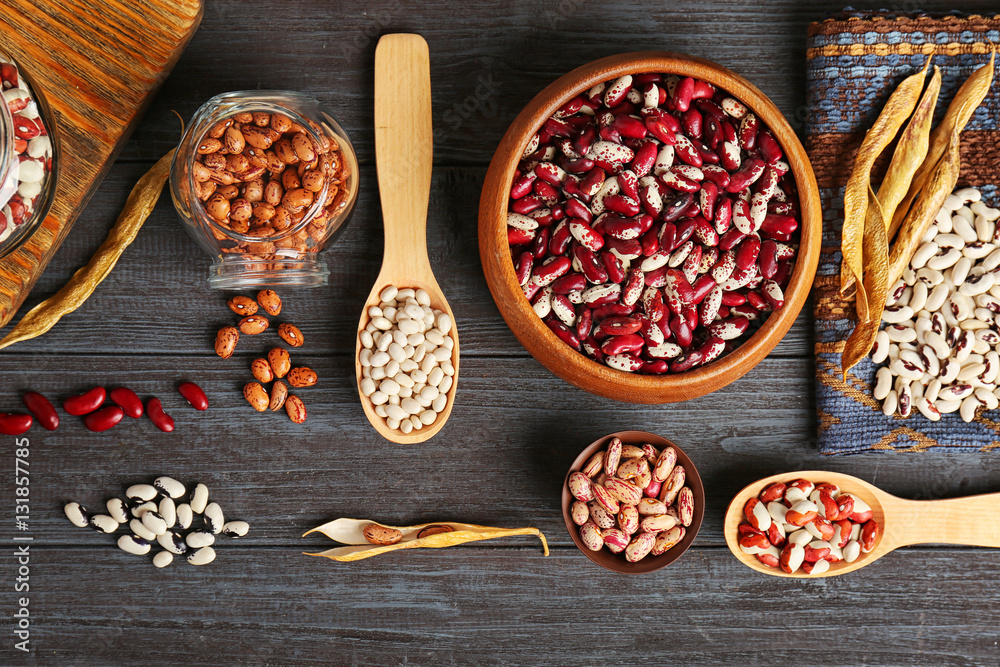 Assortment of haricot beans in bowls and spoons on dark wooden background Assortment of haricot beans in bowls and spoons on dark wooden background