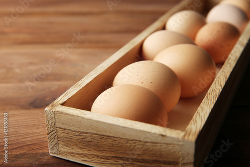Raw eggs in wooden box, closeup