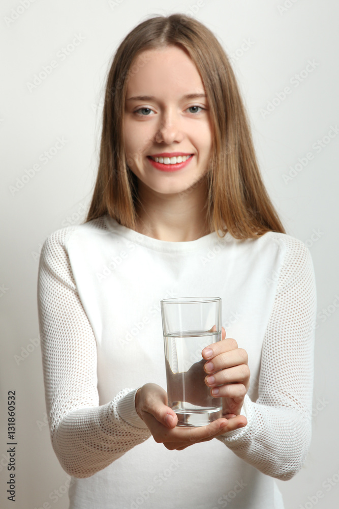 Beautiful smiling girl holding a glass of clean water.