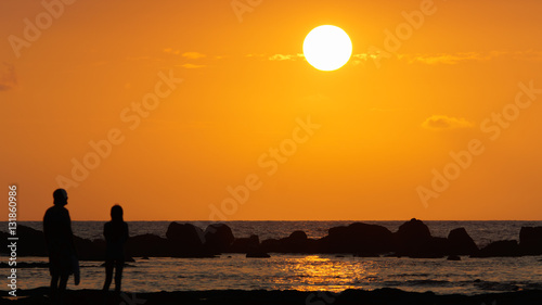 father and daughter watching sunset on Hawaii