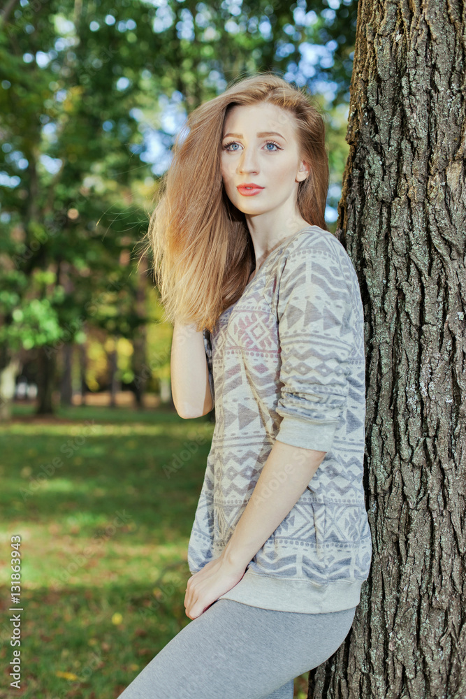 Beautiful woman with blue eyes standing in a park in autumn