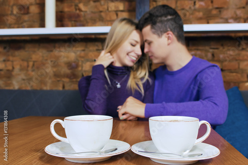 Loving young couple sitting in the cafeteria  talking and smiling. Drink hot coffee.
