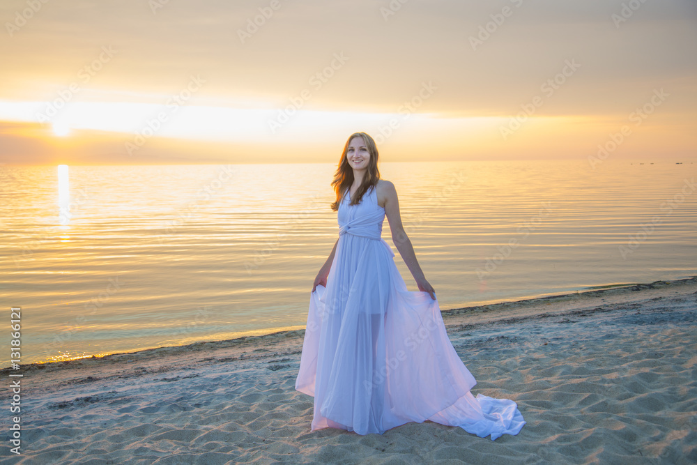 Beautiful girl in a long white dress walking on the seaside. Beautiful girl in a long white dress walking on the seaside.