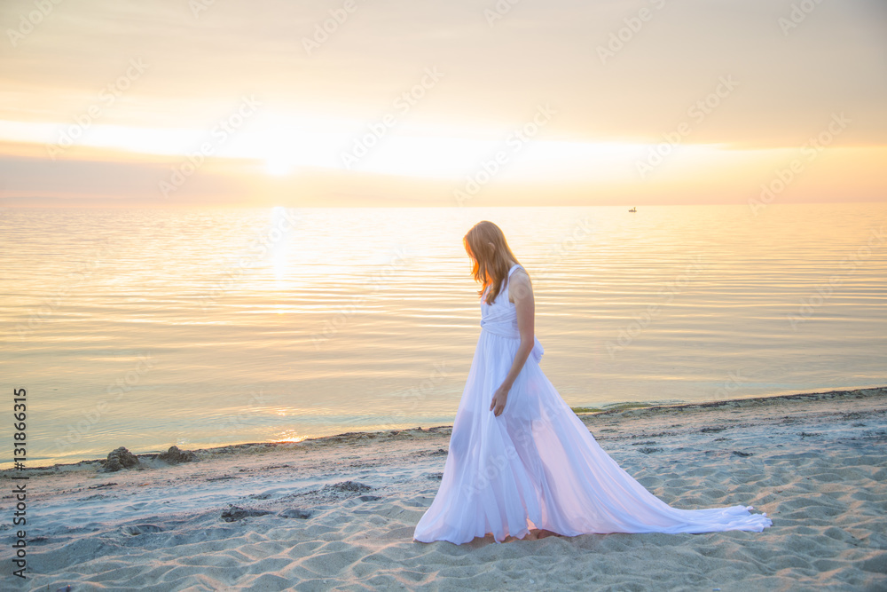 Beautiful girl in a long white dress walking on the seaside. Beautiful girl in a long white dress walking on the seaside.