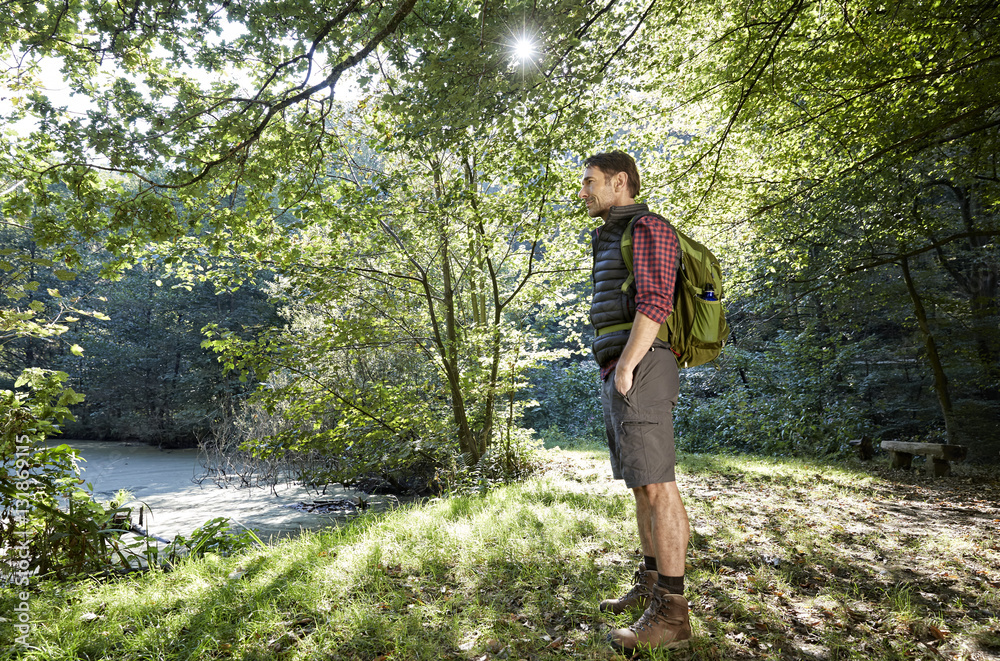 Hiker in forest looking at landscape with hands in pockets