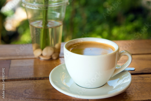 cup of fresh coffee with coffee beans on wooden table