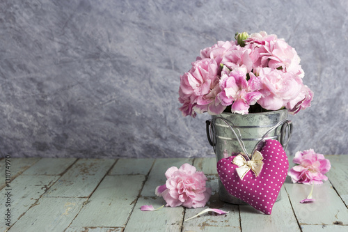 Pink heart and carnation flowers in zinc bucket on old wood