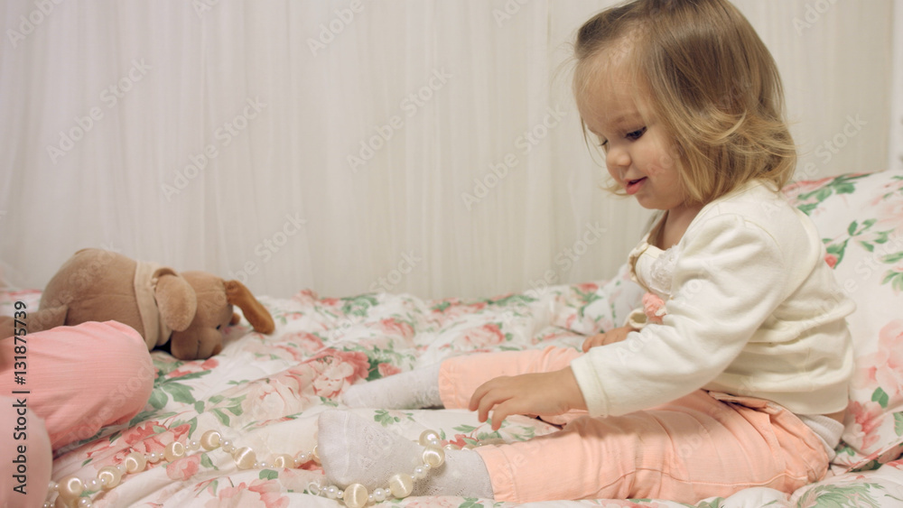 Cheerful little girls playing with beads on a bed Cheerful little girls playing with beads on a bed