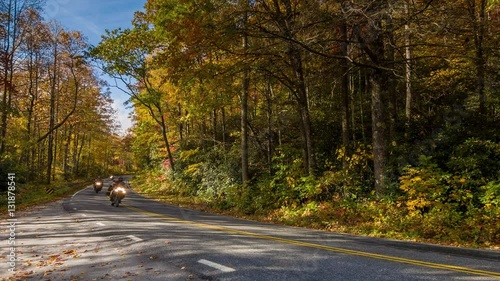 Three Motorcycles Riding on a Scenic Highway in the Blue Ridge Mountains with a Beautiful Fall Color Tree Canopy and a Blue Sky in the Morning near Asheville, North Carolina photo