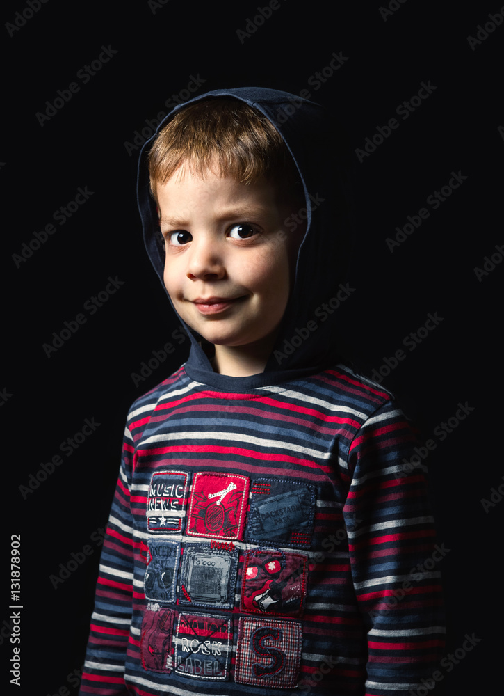 Portrait of cute boy with hoodie looking at camera over a black background Portrait of cute boy with hoodie looking at camera over a black background