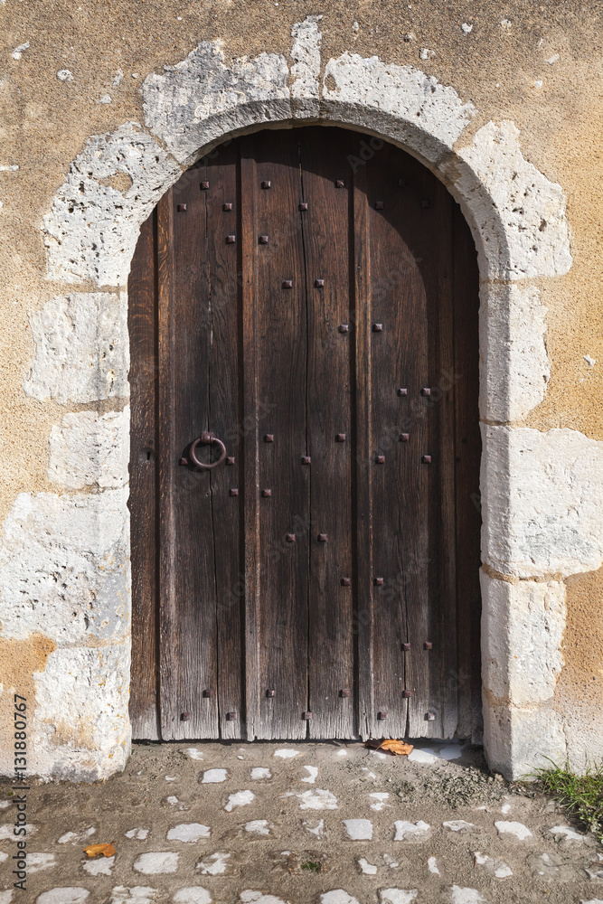 Dark wooden door with arch in old stone wall
