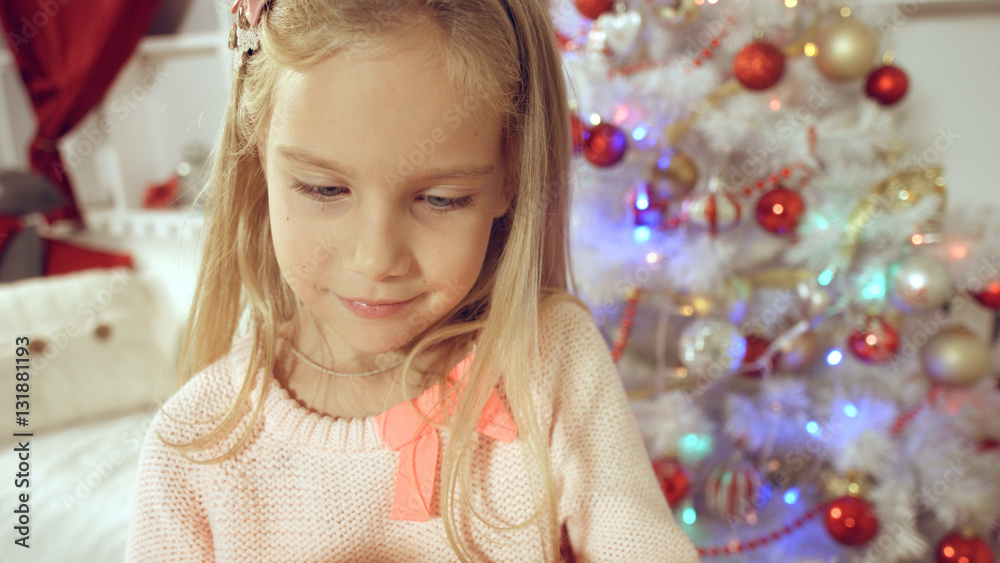 Happy little girl rejoices with a gift near the Christmas tree Happy little girl rejoices with a gift near the Christmas tree