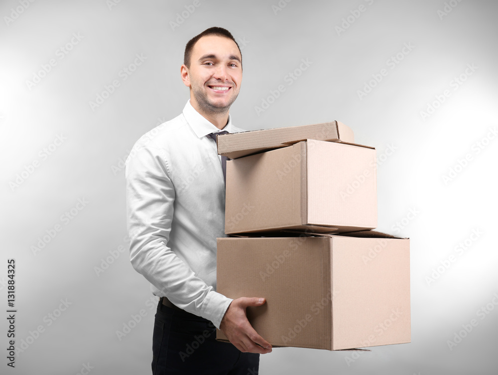 Handsome man with cardboard boxes on light background Handsome man with cardboard boxes on light background