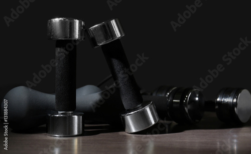 Dumbbells on wooden surface against dark background