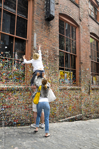 Friends helping put gum on the gumwall at the Pike Place Market in Seattle, Washington photo