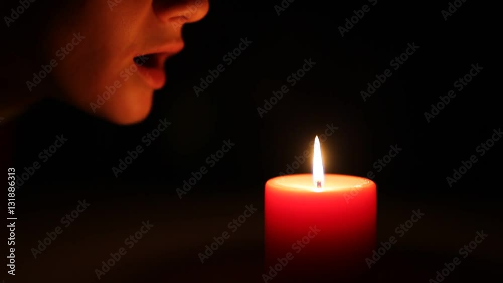 Woman blows out the candle in the dark
