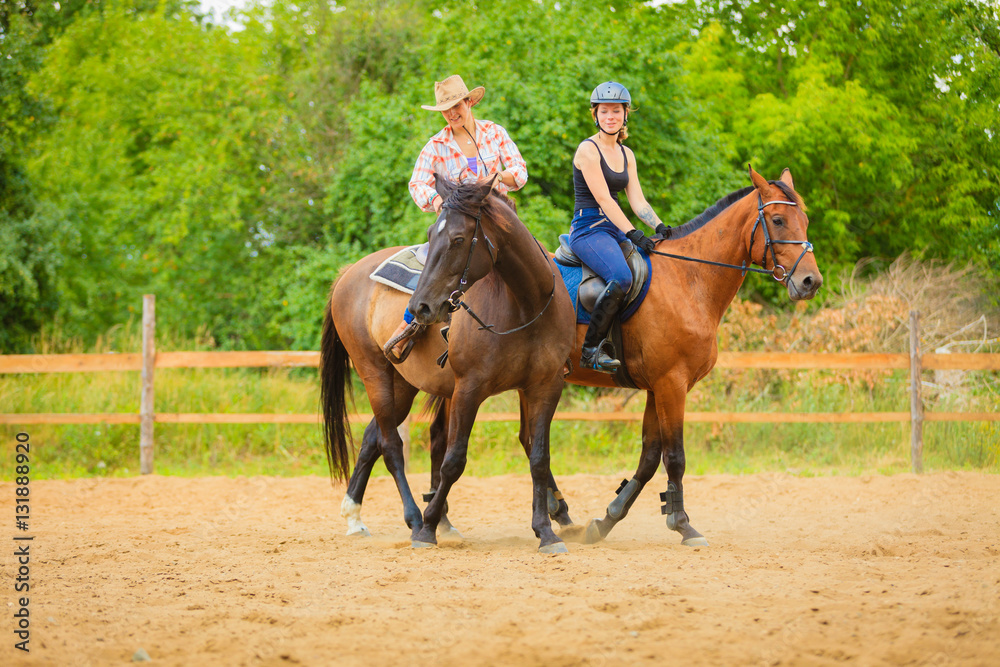 Cowgirl and woman jockey riding on horses