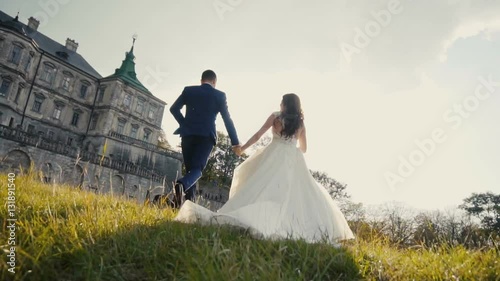Wedding couple runing on sunset before old castle