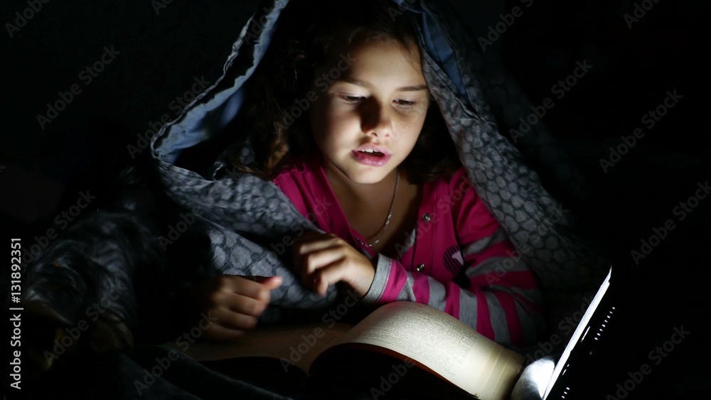 teen reading girl child reads book at night with flashlight lying under a blanket teen reading girl child reads book at night with flashlight lying under a blanket