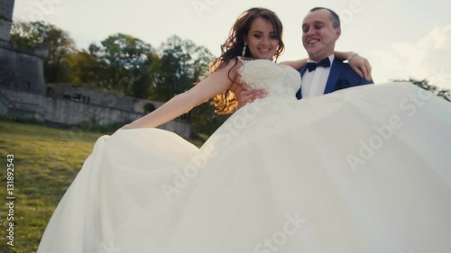 Wedding couple having fun on sunset before old castle, groom spining around with bride in hands
