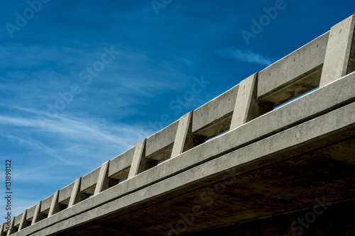 highway overpass bridge view from below against a blue sky and white clouds