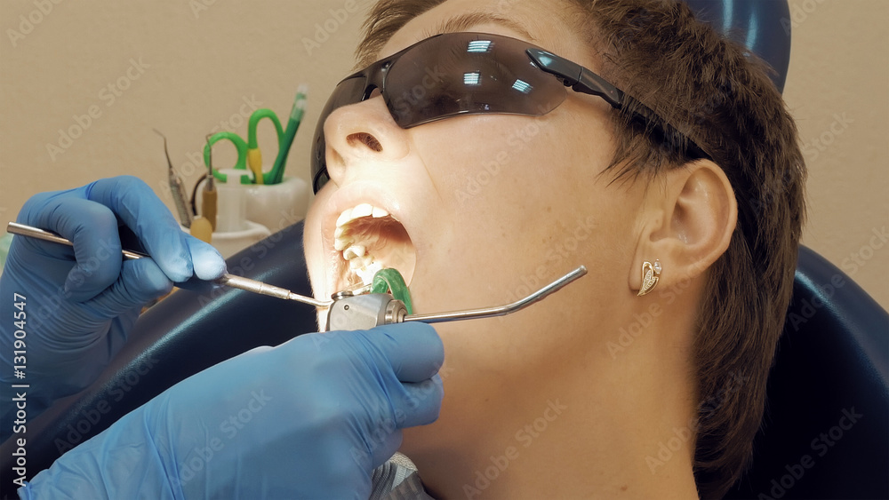 Woman at the dentist clinic office gets dental medical examination and treatment. Close up shot