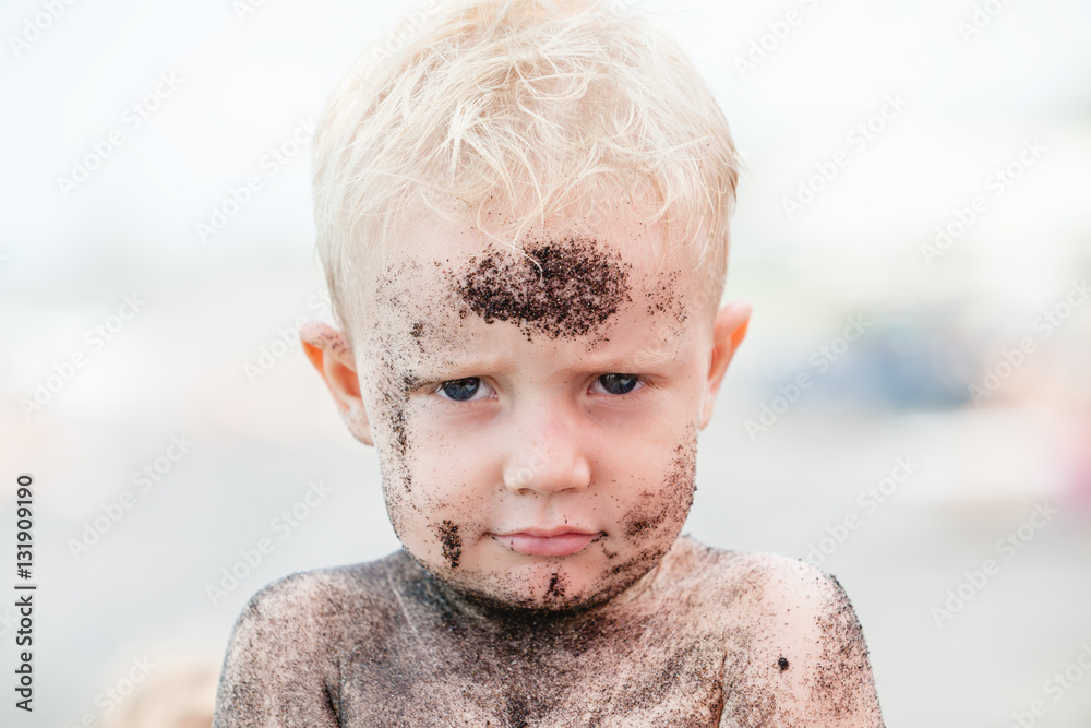 Funny photo of happy baby boy on beach with dirty face covered with black sand. Family travel, healthy lifestyle, recreation, water outdoor activity on summer beach vacation with children Stock Photo | Funny photo of happy baby boy on beach with dirty face covered with black sand. Family travel, healthy lifestyle, recreation, water outdoor activity on summer beach vacation with children Stock Photo |