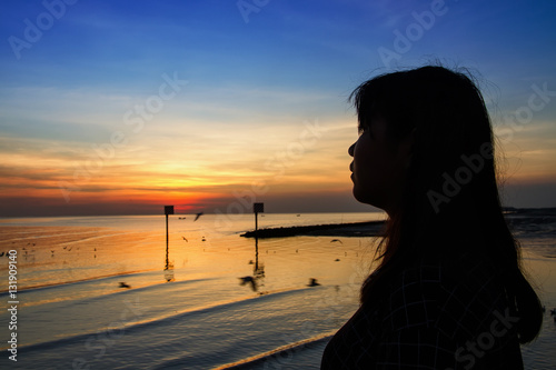 Silhouette of teenage woman standing on white cement bridge fish