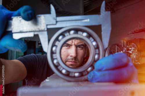 Close up of mechanic using a vernier caliper to measure a ball bearing photo